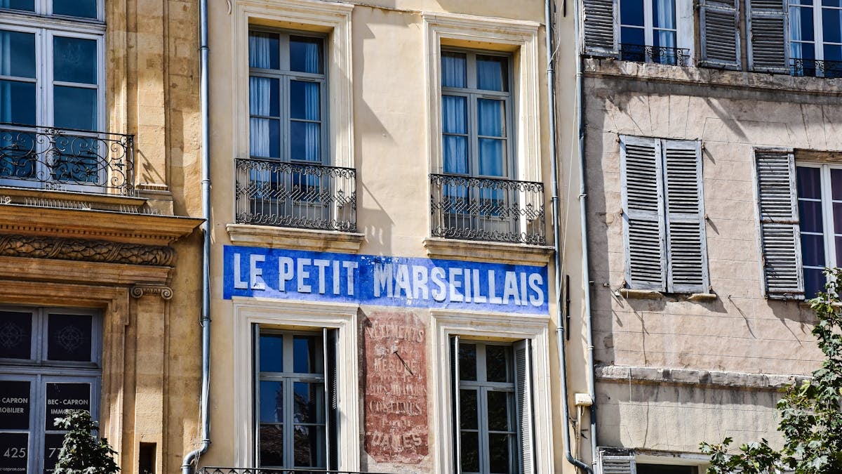 Charming building front with 'Le Petit Marseillais' in Aix-en-Provence, France.